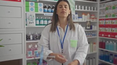 Eczanede kolları çaprazlanmış, laboratuvar önlüğü giymiş, çeşitli kimyasallarla dolu rafların arasında güvenle duran genç ve güzel bir İspanyol kadın..