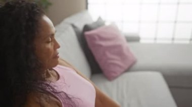 Rahat bir oturma odasında, pembe yastıklı, sakin ve rahat bir kadın.