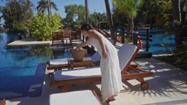 Bali 'de lüks bir tatil köyü havuzunun yanında uzanan güzel genç bir kadın rahatlık ve zarafeti somutlaştırıyor..
