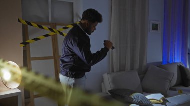 Odanın içinde loş bir suç mahallini araştıran Afrikalı bir adam uyarı bandıyla odanın öbür tarafına geçti.