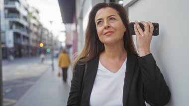 Çekici İspanyol kadın canlı bir caddede akıllı telefon kullanıyor..