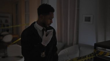 Takım elbiseli bir erkek dedektif, arka planda polis bandıyla birlikte olay yerindeki bir ses mesajını kaydediyor..