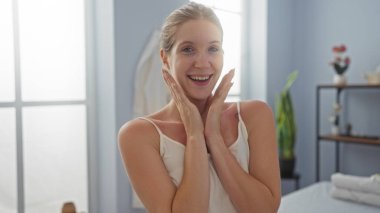 Genç bir kadın mutlu ve rahat görünüyor. Parlak bir iç mekanı olan bir kaplıcada.