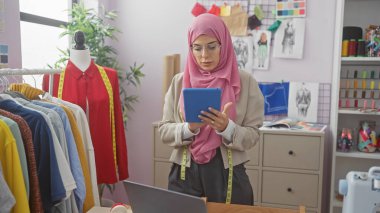 Modern atölyesinde renkli giysiler ve dikiş aksesuarlarıyla çevrili bir kadın terzi..