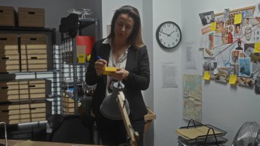 İspanyol kadın dedektif, elinde fotoğraf ve notlar olan bir polis karakolundaki kanıtları inceliyor..