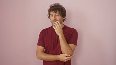 Pembe arka planda sakallı, düşünceli ve düşünceli bir tavır sergileyen düşünceli genç İspanyol bir adam..