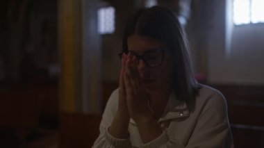 Genç bir İspanyol kadın İtalya 'da güzel aydınlatılmış bir Hıristiyan kilisesinde dua ediyor. Sadakatini ve barışçıl davranışlarını vurguluyor..