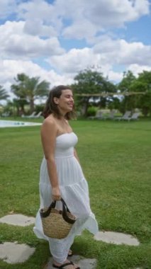 Beyaz elbiseli genç İspanyol kadın Puglia, İtalya 'da manzaralı ve yemyeşil bir villada güneşli bir günün tadını çıkarıyor..