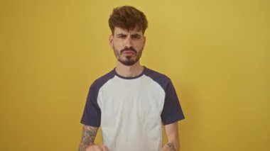 Dehşete düşmüş ifadeyle korkuyu ifade eden genç bir İspanyol. Ellerini kaldırdı ve panik içinde bağırdı. Sarı arka planda tek başına duruyordu.