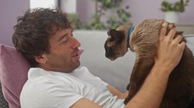 Genç İspanyol bir adam, kahverengi kedisiyle oynaşmaktan zevk alıyor. Kapalı bir ortamda kaynaşıyor..