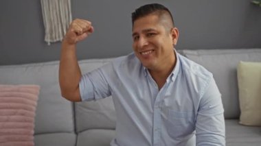 Genç adam evin oturma odasında kanepede otururken gülümsüyor ve kaslarını esnetiyordu.