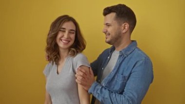 İzole edilmiş sarı arka planda kucaklaşan mutlu çift sevgi, birliktelik ve neşe gösteriyor.