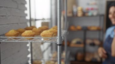 Pastanede telefonla konuşan bir kadın, arka planda kek ve hamur işleri rafları var.
