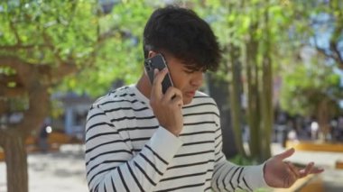 Genç İspanyol bir adam şehir parkında güpegündüz telefon görüşmesi yapıyor..