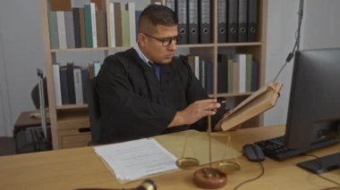 Genç yargıç kitap okuyor ve masanın üzerinde tokmak ve teraziyle bir ofiste evrakları imzalıyor.