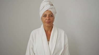 Havlu ve bornozlu neşeli orta yaşlı kadın soyutlanmış beyaz arka planda gülümsüyor, gülüyor ve gülümsüyor.