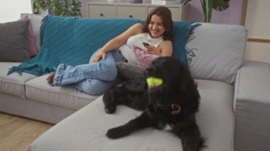 Genç bir İspanyol kadın rahat bir oturma odasındaki kanepede uzanıyor. İçerideki labrador köpeğiyle..
