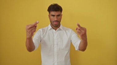 Beyaz gömlekli genç adam iki eliyle sarı bir arka plana kaba bir hareket yapıyor. Öfke ve hayal kırıklığını ifade ediyor..