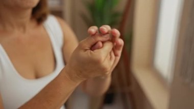 Doğal ışık ve rahatlama için yeşil bitkilerle dolu sakin spa odasındaki ellere losyon süren kadın..