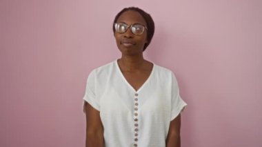 Gözlüklü, düşünceli, düşünceli genç Afro-Amerikalı kadın. Çene üstüne düşünceli, soyutlanmış pembe arka plan üzerinde düşünceli bir ifade. Şüpheli sorular soruyor.