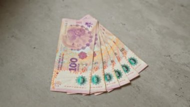 Arjantin 'in canlı tasarım ve ekonomi unsurlarını finansal bağlamda gösteren somut bir zemine serpiştirilmiş Arjantin pesoları.