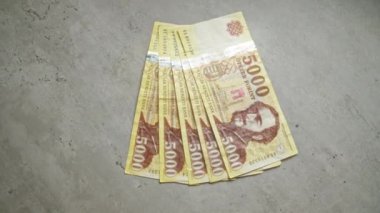 Macar 5000 forint banknot düzgün bir şekilde beton bir yüzeye yerleştirilmiş, para birimi detayları ve hungary 'deki yasal ihaleyi vurguluyor.