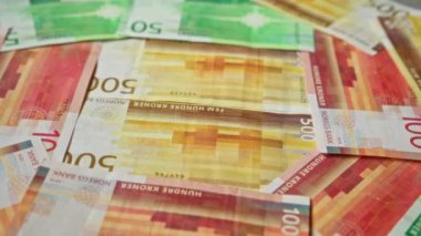 Norveç banknotları 50, 100 ve 500 kron dahil olmak üzere çeşitli banknotlar çerçeveye yayıldı ve norges bankasından modern para birimi tasarımı sergilendi..