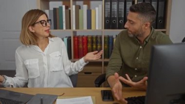 Kadın ve erkek, kitaplarla ve profesyonel belgelerle çevrili bir ofiste iş konuşuyorlar..