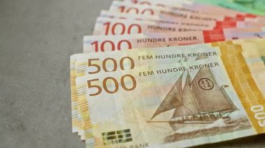 Beton bir yüzey üzerinde sergilenen Norveç kroneri banknotları 50 ila 500 arasında çeşitli değerleri vurgular.
