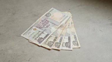 Beton bir yüzeye dizilmiş çeşitli banknotlar halinde Mısır banknotları, para biriminin karmaşık tasarım unsurlarını sergiliyor.