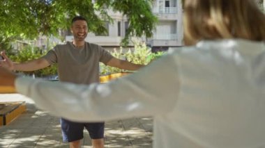 Erkek ve kadın güneşli bir günde açık şehir parkında neşeli bir kucaklaşmayı paylaşıyorlar.
