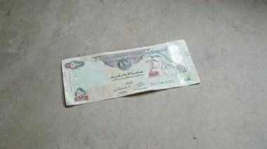 Birleşik Arap Emirlikleri, paraların karmaşık tasarım ve detaylarını gösteren somut bir yüzey üzerinde Dirham banknotunu yayınladı..