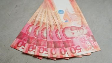 Filipinler 'e özgü canlı tasarım unsurları ve para birimi detaylarını gösteren somut bir yüzey üzerine yayılmış Filipin pesoları..