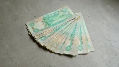 Çoklu uae dirhams banknotları bir beton yüzey üzerinde fan gibi düzenlenmiş, emirati para biriminin canlı tasarımı ve ayrıntıları vurgulanıyor.