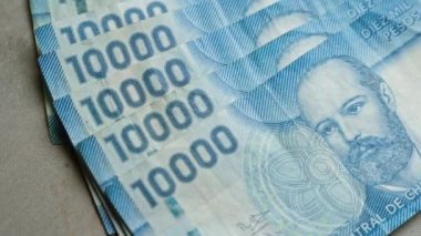 Şili banknotları düzgün bir şekilde beton bir yüzeye dizilmiş, mavi 10,000 peso banknotlar yakın çekim görüntülerinde belirgin bir şekilde sergilenmektedir.