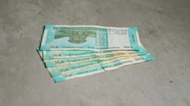 Hindistan 'ın finansal temalarını yansıtan, para biriminin tasarımı ve detaylarını vurgulayan, somut bir zemine düzgünce yerleştirilmiş 50 rupilik banknotlar..