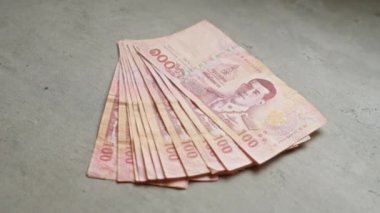 Thai baht banknotlarının yakın plan çekimleri beton bir yüzeye yayılarak Tayland 'dan gelen para birimini ayrıntılı portrelerle gözler önüne serdi..