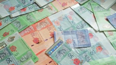 Çeşitli banknotlarda dağılmış Malezya ringgit banknotları canlı tasarımlar ve ulusal sembollerin yer aldığı renkli bir para birimi görüntüsü yaratıyor