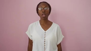 Gözlüklü genç Afro-Amerikalı kadın. Tamam, parmaklarıyla işaret ediyor. Yüzünde şok olmuş ve şaşırmış bir ifade var.