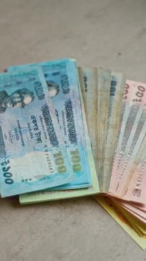 Bangladeş banknotları somut bir yüzeye yayılmış, canlı renkler ve detaylı tasarımlarla çeşitli mezhepler sergiliyor, Bangladeş 'te kullanılan para birimini vurguluyor.