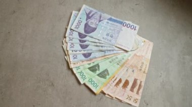 Güney Kore banknotları beton bir yüzeyde fan şeklinde dizilmiş, renkli para birimi değerleri sergiliyor.