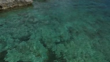 Torre Dell 'orso, Salento, Puglia, İtalya' daki kayalık sahil kenarındaki kristal berrak turkuaz suları sakin bir kıyı manzarası sergiliyor..