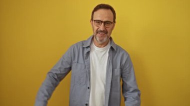İspanyol bir adam, orta yaşlı, gözlük takıyor, ayakta duruyor ve elleriyle çerçeveliyor - izole edilmiş sarı arka planda mutlu bir fotoğraf için yaratıcı fotoğraf konsepti