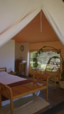 Afrika doğasında güzel bir çadır, rahat bir yatak, ahşap mobilyalar, huzurlu bir dekor ve sakin bir kamp macerası için davetkar bir açık hava manzarası..