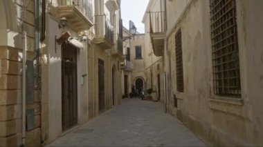 Lecce, Puglia, İtalya 'da sessiz bir ara sokak, eski mimari, balkonlar ve sokağa park etmiş bir scooter..