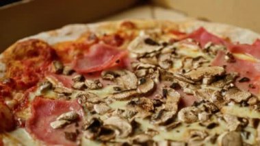 Lezzetli bir mantara yakın çekim ve açık bir kutuda jambonlu pizza, lezzetli malzemeler ve erimiş peynirin altını çiziyorum.