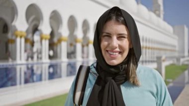 Abu Dabi Camii 'nde tesettürlü gülümseyen kadın, İslami mimari sergiliyor ve uae' de seyahat ediyor..