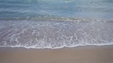 Yumuşak dalgalar, sakin bir sahil sahnesinde, doğayı, sükuneti ve okyanusu tasvir eder..