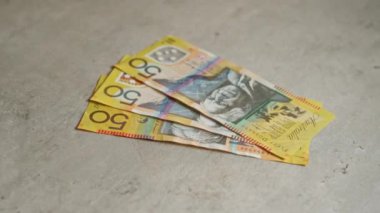 Avustralya banknotları, Avustralya 'da beton zemin üzerinde sergilenen, canlı 50 dolarlık banknotlar, somut arka planda para ve finansmanı vurguluyor.