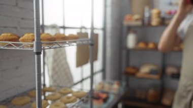 Orta yaşlı bir adam fırında telefonla konuşuyor. Etrafı hamur işleri ve ekmeklerle çevrili. Tuğla odasındaki büyük pencerelerden içeri güneş ışığı giriyor.